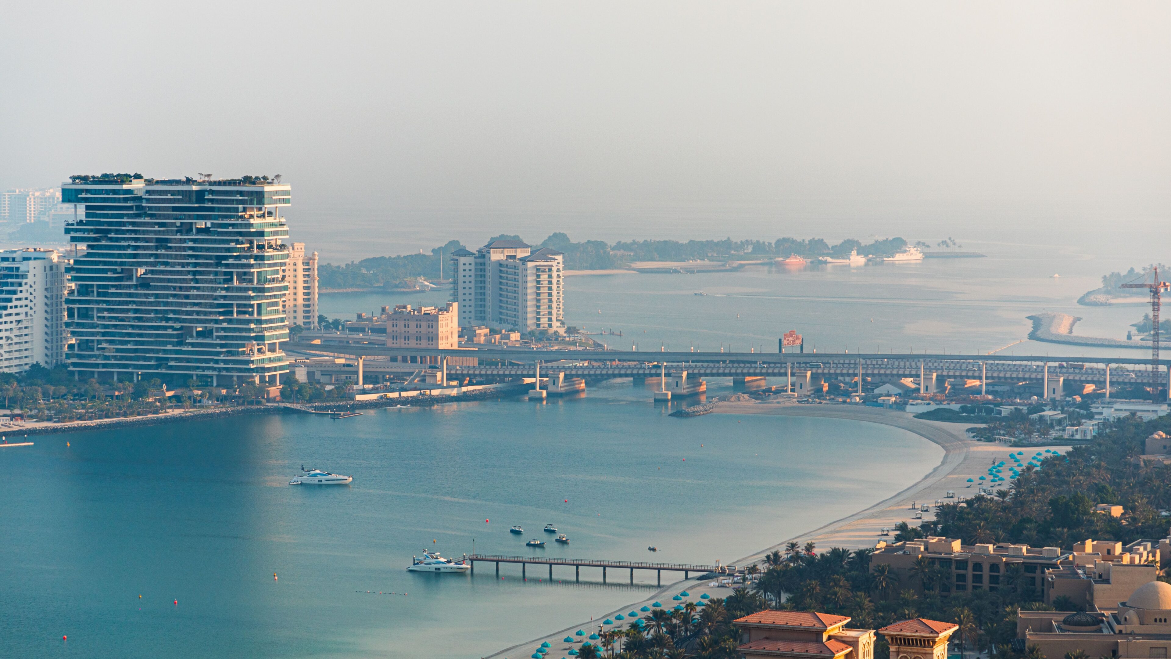 Dubai coastline with a beach, a pier and city towers