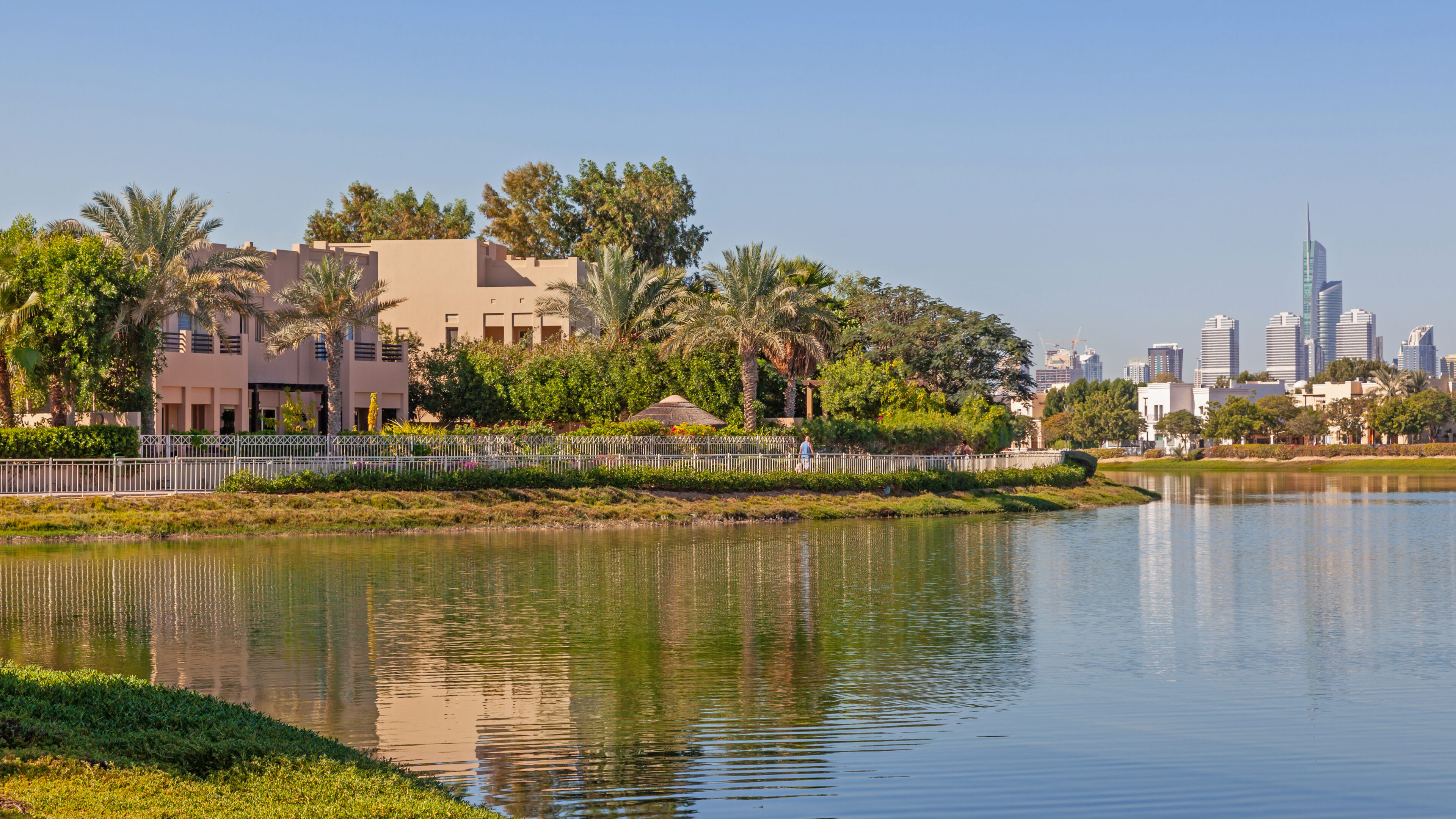 Villas behind palm trees, reflected in a lake in Dubai