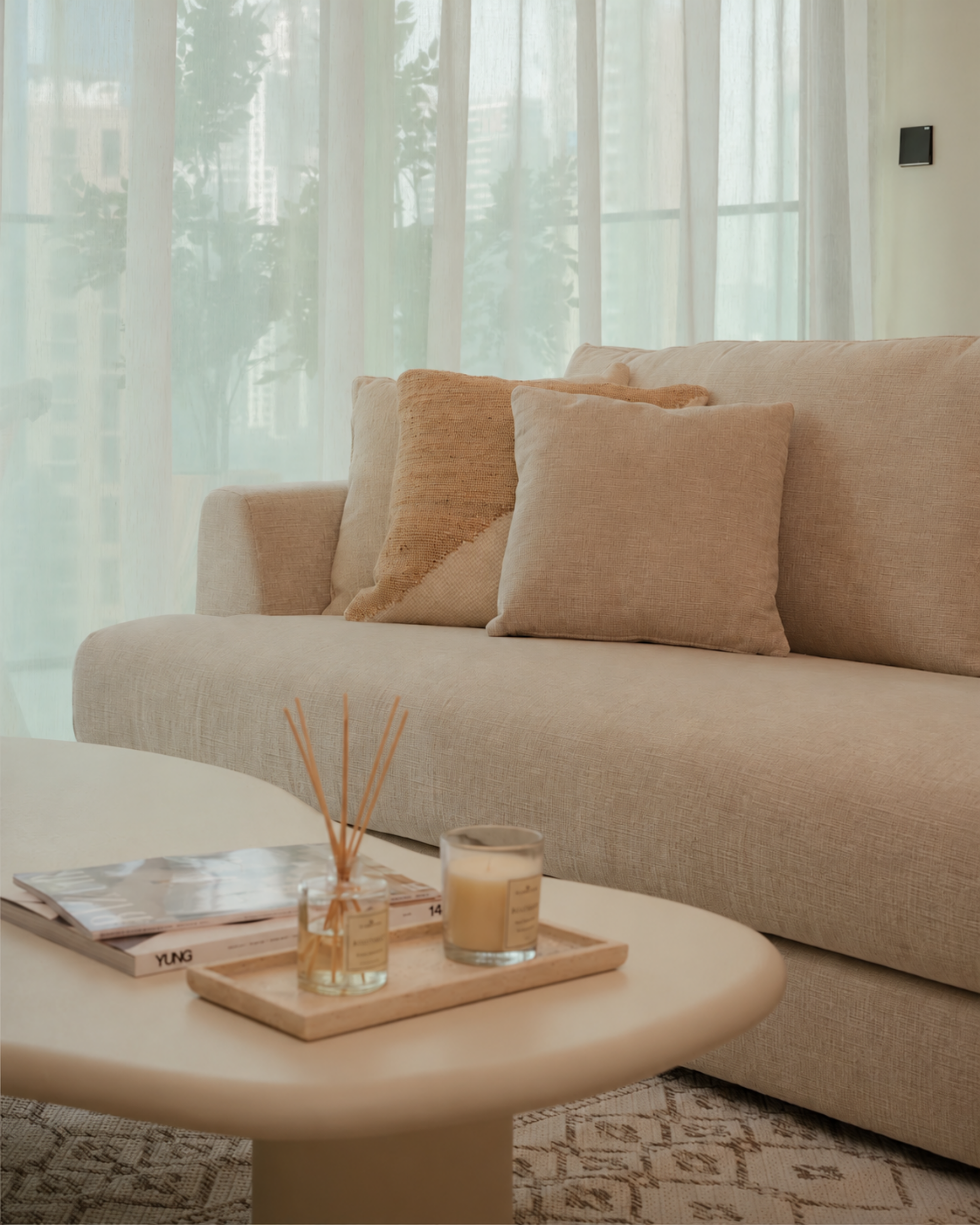 Living room in a property prepared by EAP, with a beige sofa, cushions and a tray with a diffuser and candle