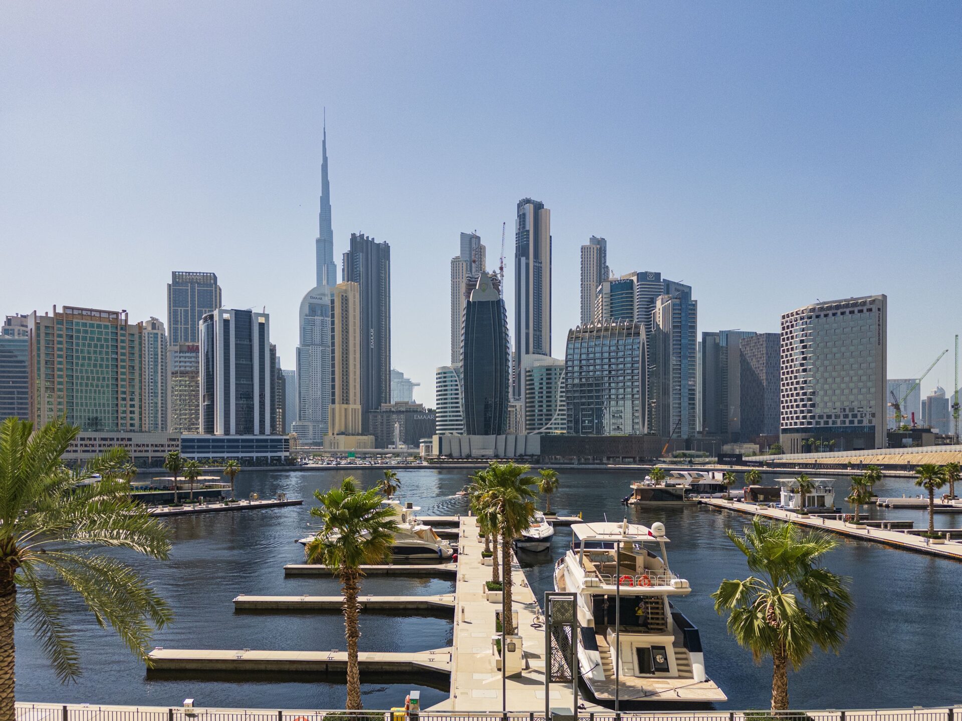 Dubai skyline with the Burj Khalifa above a marina lined with palm trees